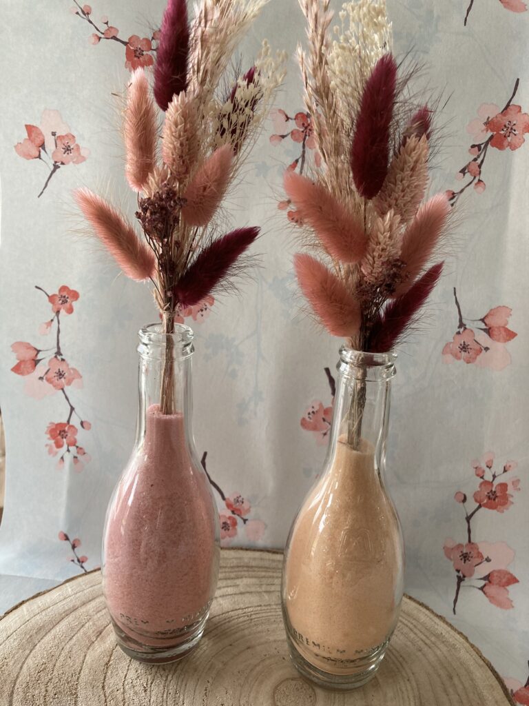 Vaasje met gekleurd zand en droogbloemen
